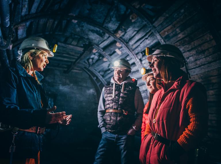 Personen in einer Mine, die einem Guide zuhören.