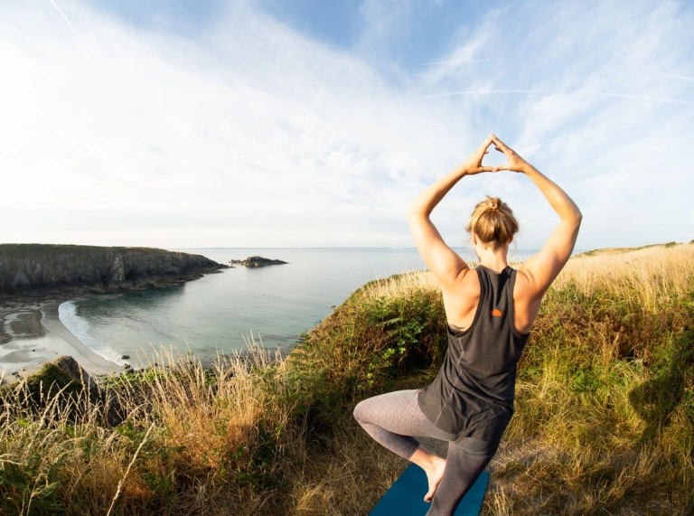 Person doing yoga overlooking beach.