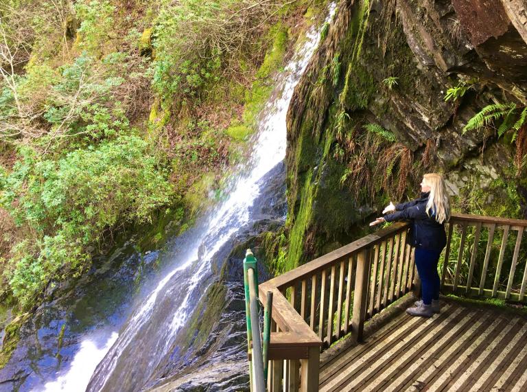 Woman on a viewing platform looking at a waterfall.