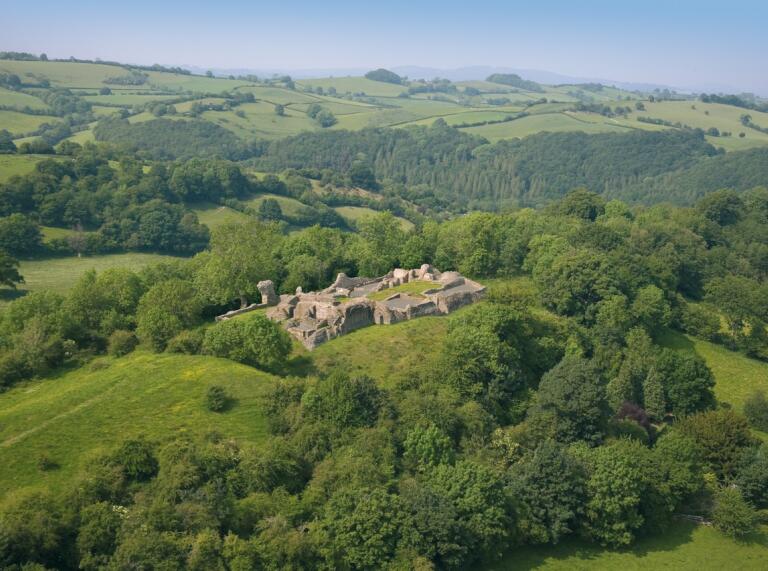 Aerial view of the ruins of Dolforwyn Castle, surrounded by green countryside.