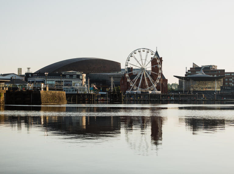A view of Cardiff Bay from the water showing buildings and a big wheel