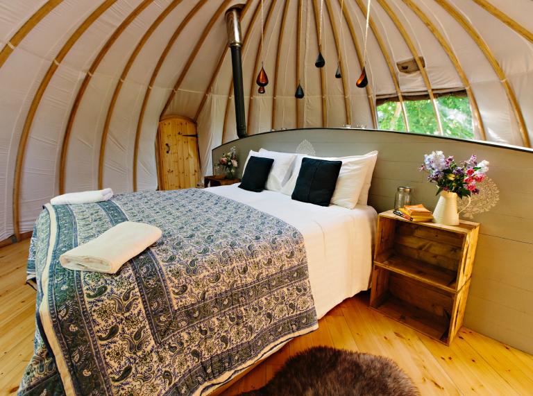 A bed with a side table inside a glamping pod
