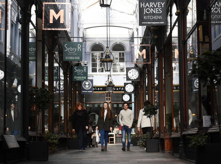 Menschen, die durch eine viktorianische Arkade schlendern.