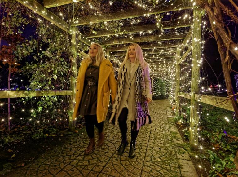 two females walking through archway with multiple lights.