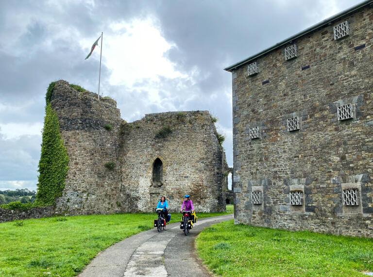 Two people cycling passed a castle.