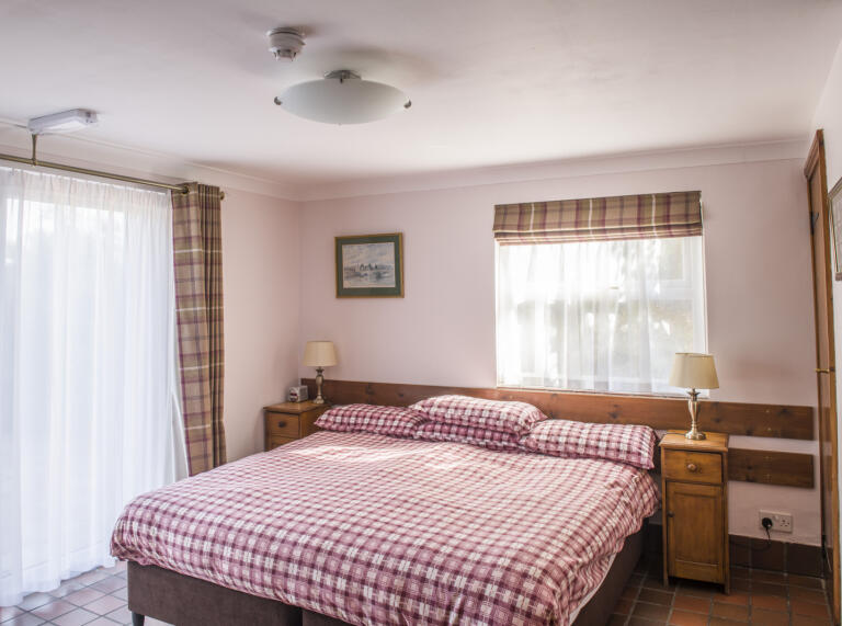 A large double bed in a room with a patio door.