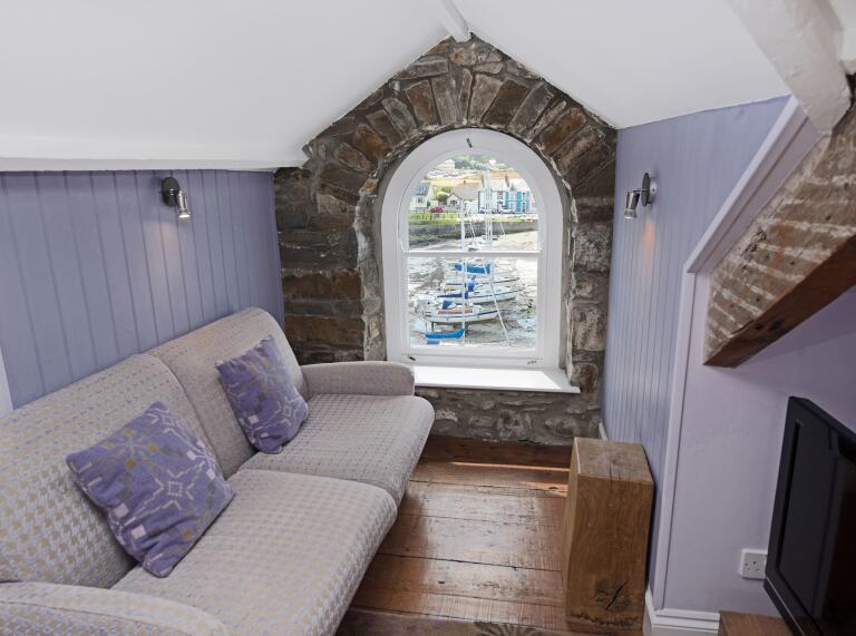 room with sofa, TV and arched window with harbour view.