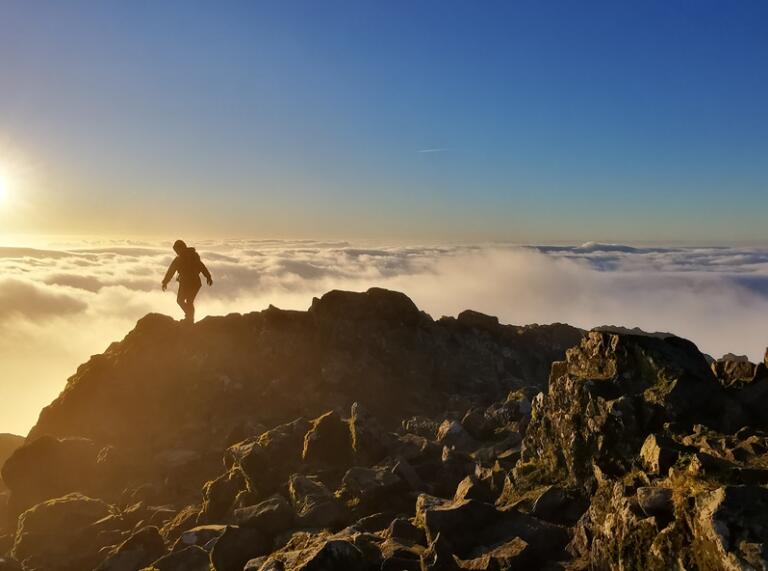A person above the clouds on top of a mountain