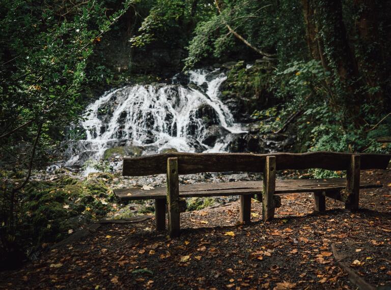 wooden bench in front of waterfall.