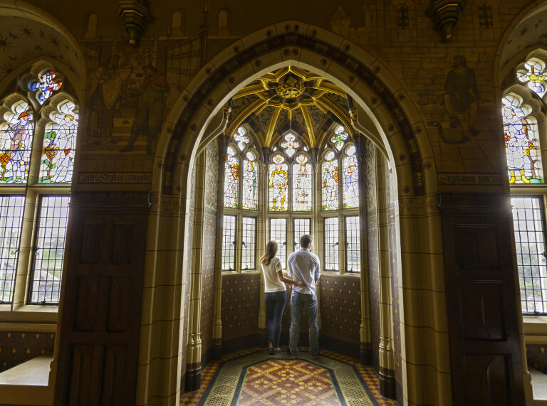 Zwei Personen stehen im Schloss und schauen aus dem Fenster.