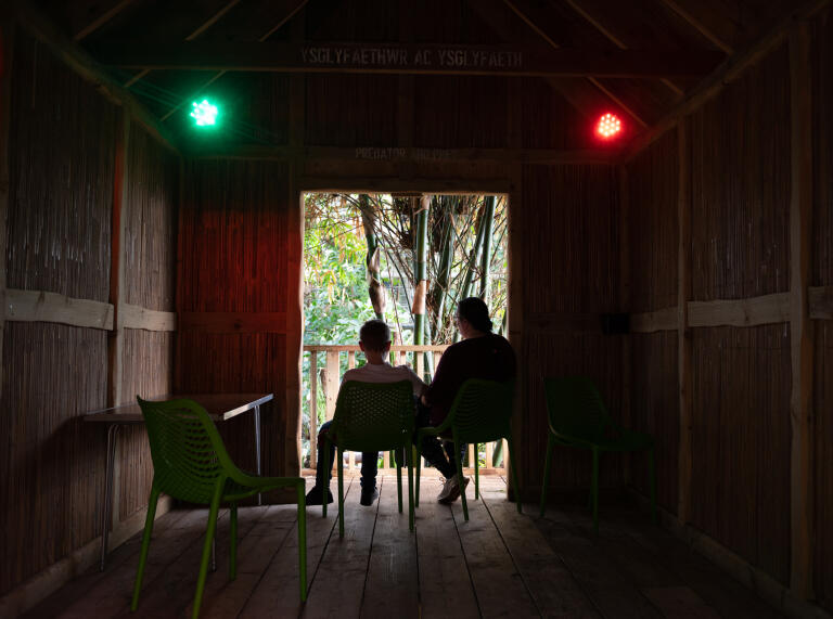 Two people sitting in a dark tree house.