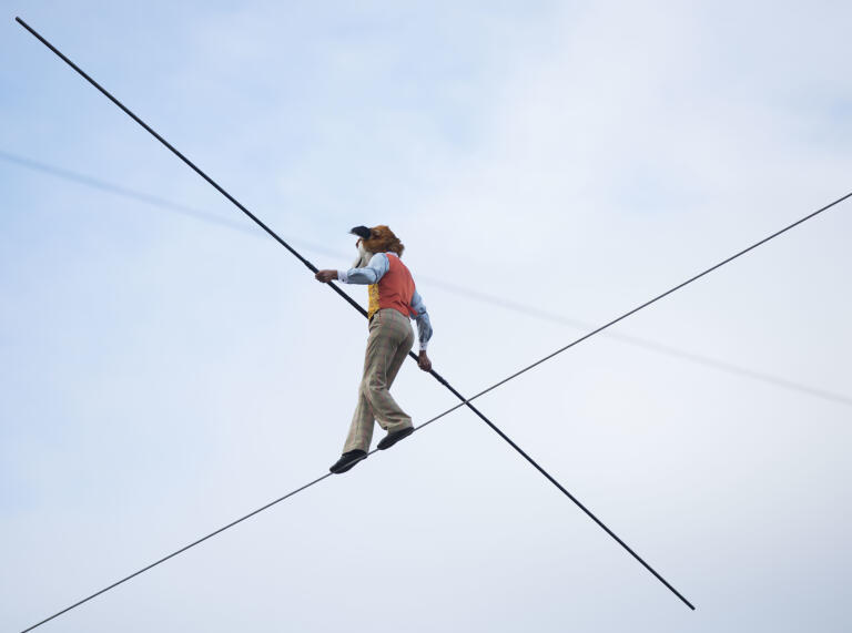 A man dressed as Fantastic Mr Fox walking along a tight rope.