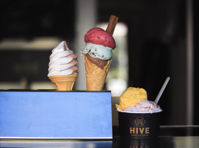 Three different ice creams in cones and tubs.