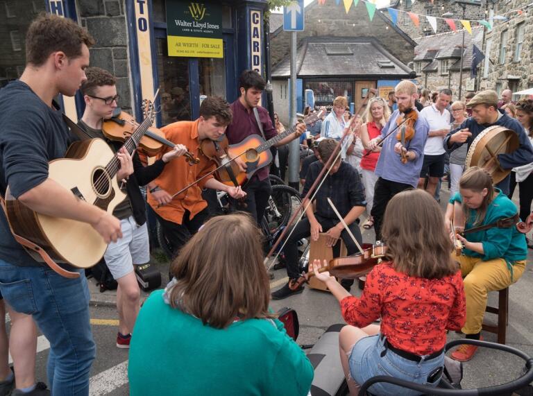 Group of young people jamming outside a pub in a town centre.