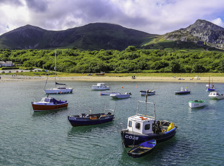 Fishing boats moored in a harbour, with mountains in the background.