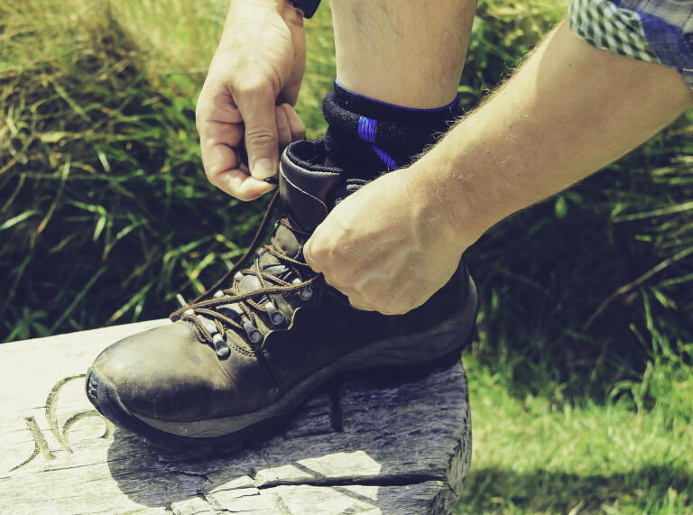A man doing up hiking boot laces.