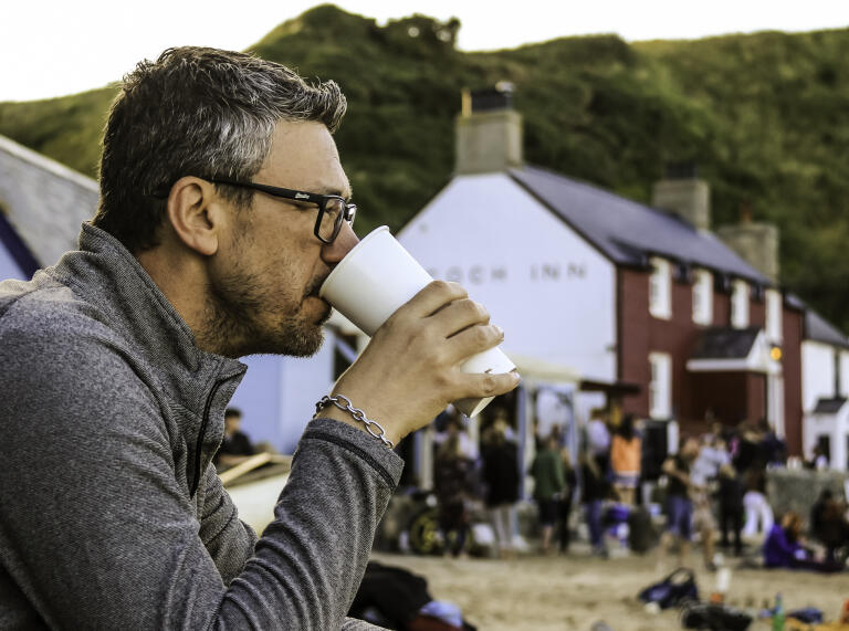 A man having a drink outside a beach front pub.