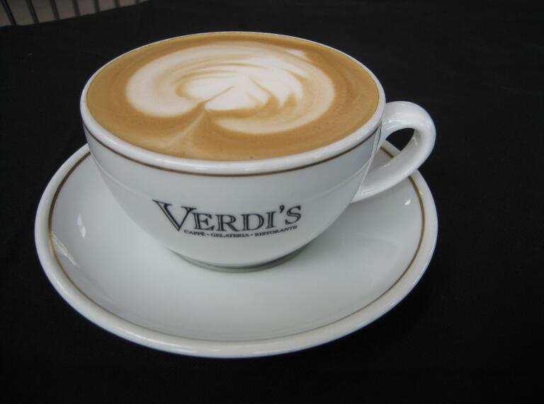 Cup of coffee with Verdi's on cup and saucer.