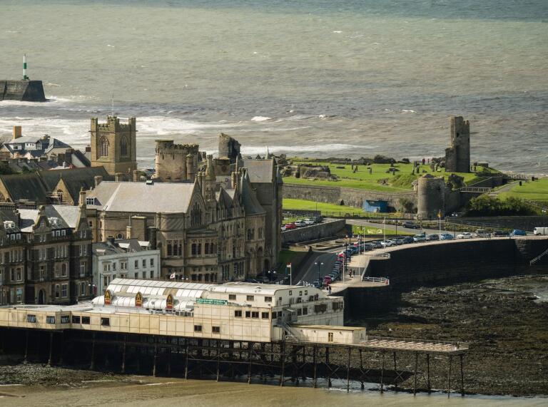 Aerial view of a seaside pier, promenade and castle.