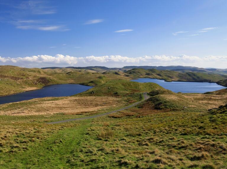 Two large mountain top lakes among green moorland.