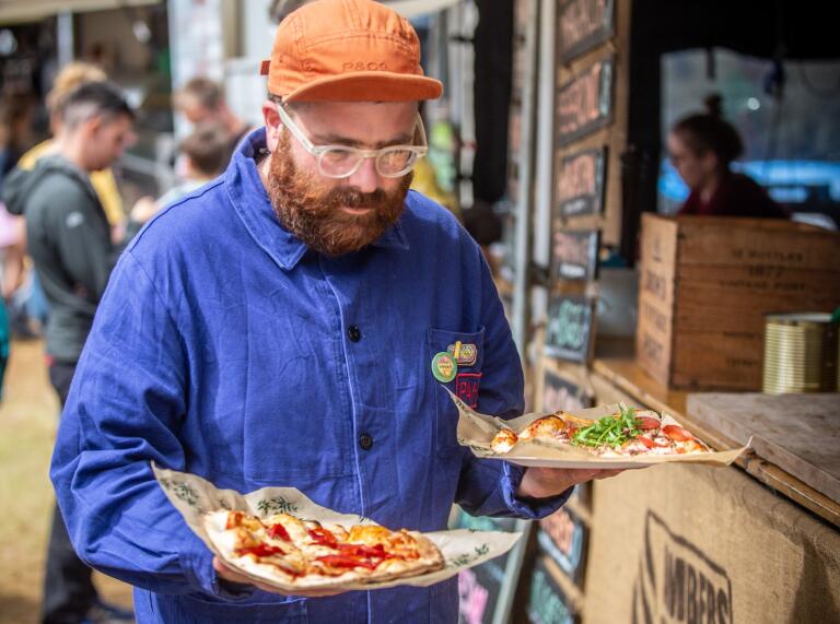 A man carrying two pizzas.