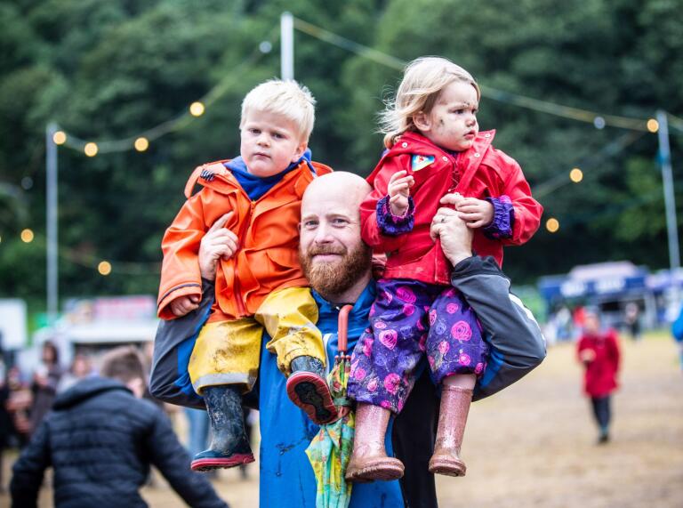 Ein Mann trägt zwei Kinder über das Festival.