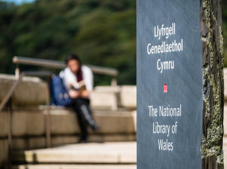 Signpost for the National Library of Wales with a blurred person in the background