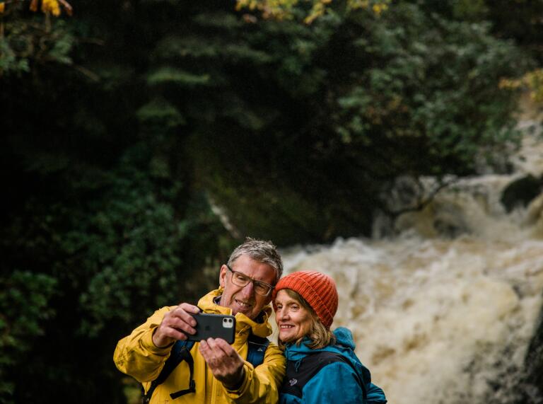 Ein Paar macht ein Foto von sich selbst mit einem Wasserfall im Hintergrund