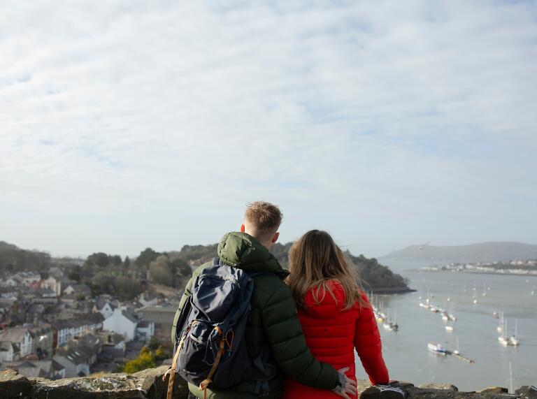 man and woman stood in castle with view of sea and boats.