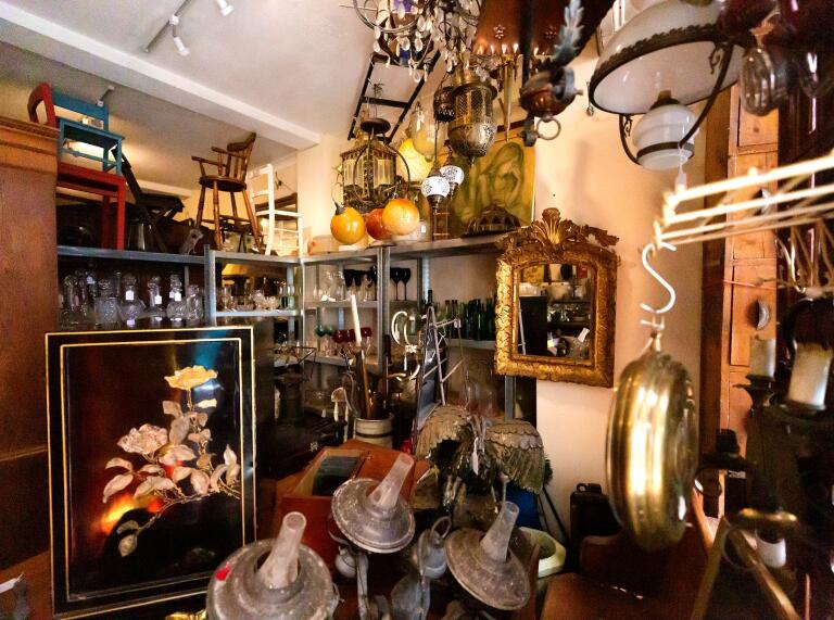 Im Inneren eines Antiquitätengeschäfts sind alte Lampen, Möbel und Gemälde ausgestellt.