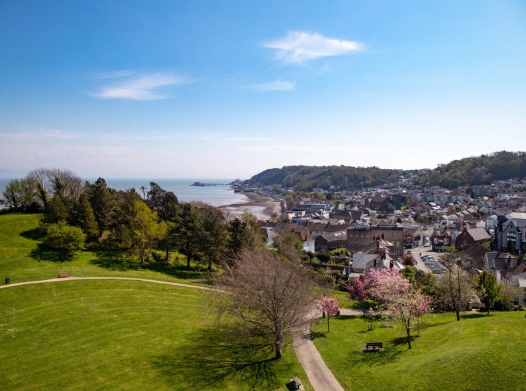 A coastal town seen over a grassy hilltop. 