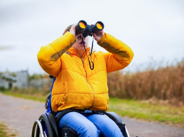 male in wheelchair using binoculars.