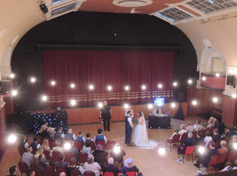 wedding scene in a historic-looking hall.
