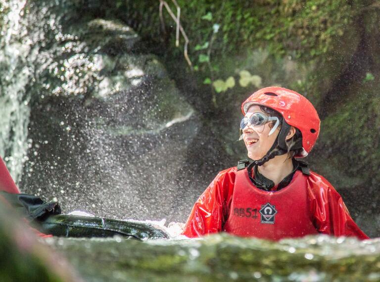 Close up of teens in helmets and wetsuits in a river having fun