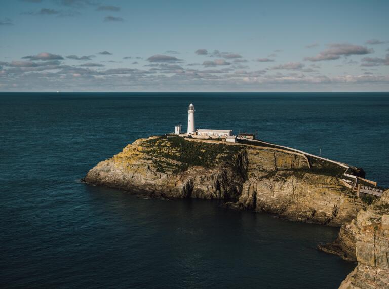 A white lighthouse tower on a rocky peninsula.