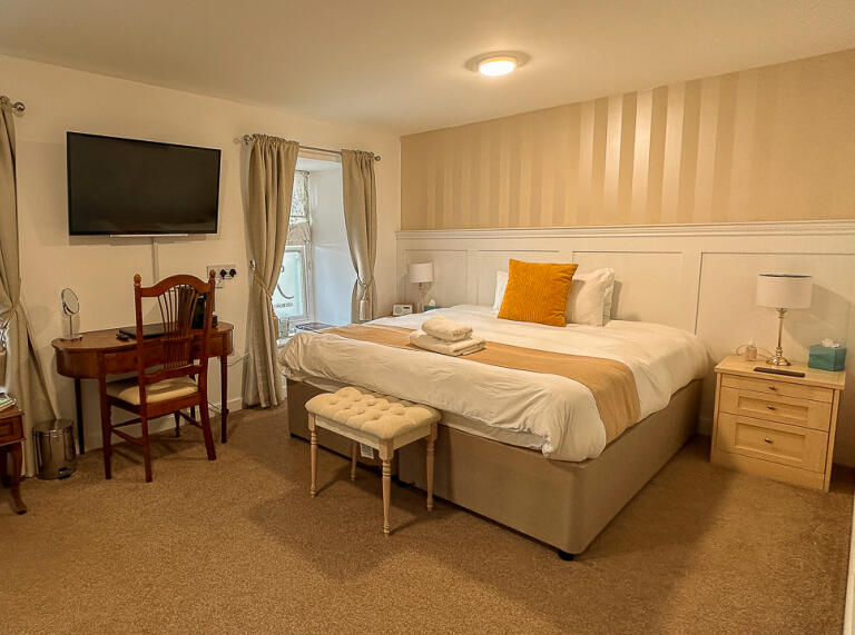 Ein Hotelzimmer mit cremefarbenem und gelbem Dekor und einem dunkleren Teppichboden..