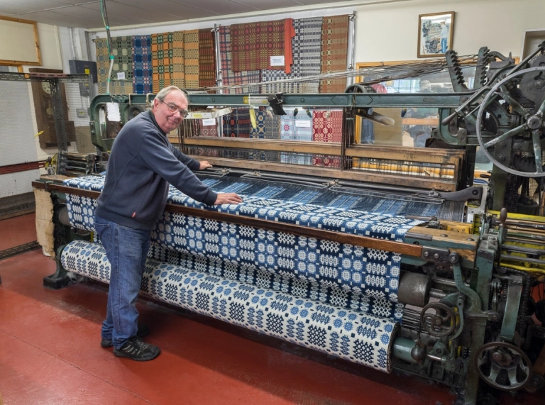 A weaver working on a weaving loom making traditional Welsh geometric colourful fabrics 