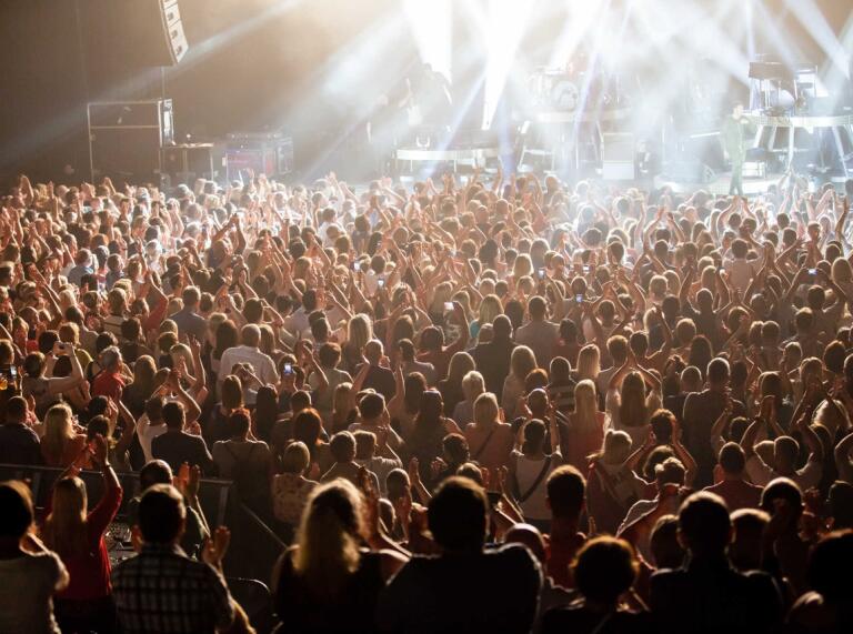 View towards the stage across the heads of a crowd of people watching a pop concert