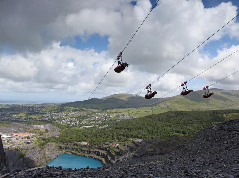 Four people zip lining over a quarry.