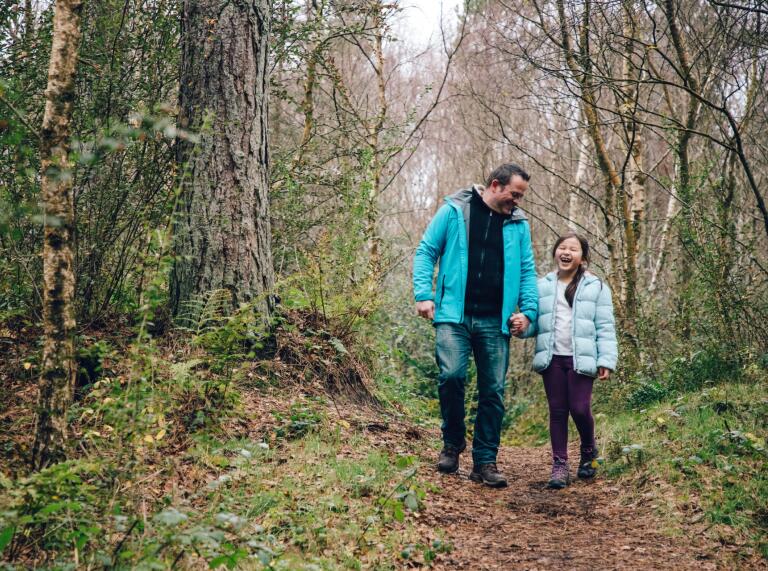 father and daughter walking in forest.