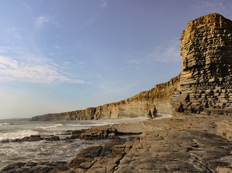 Hohe Felsklippen mit Steinformationen und dem Meer.