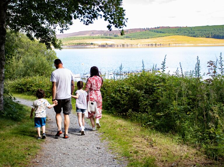 family walking along path by lake.