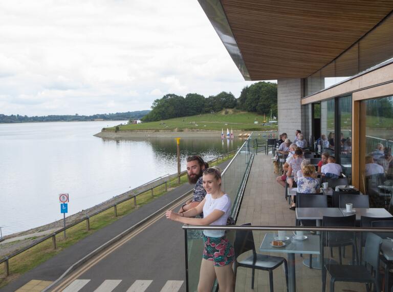 visitor centre near lake, with people stood and sat outside.