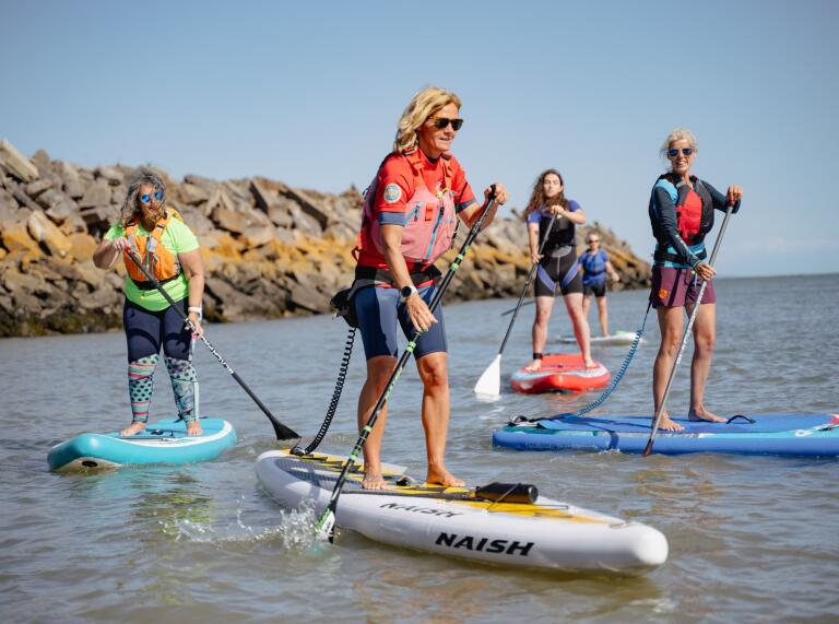 group of women stand up paddleboarding.
