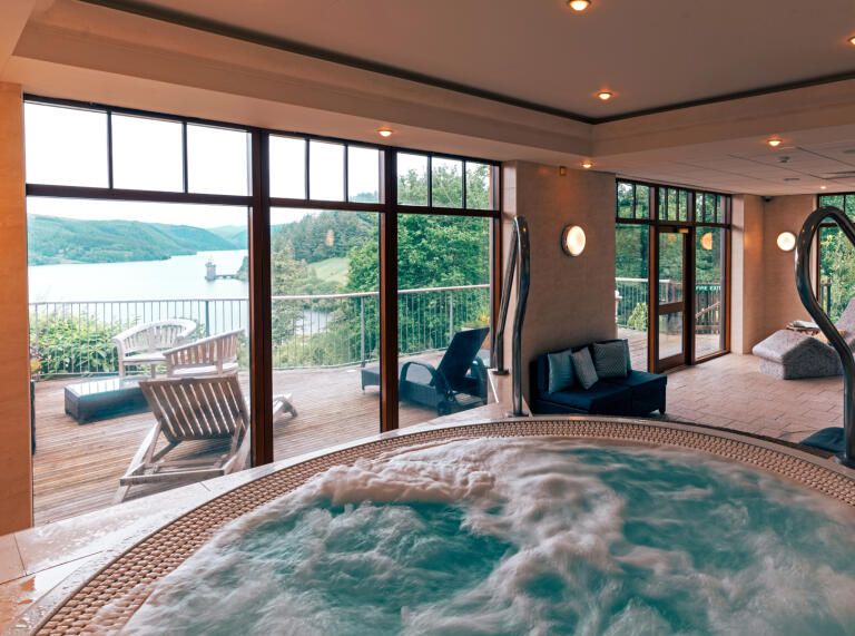 An indoor whirlpool spa pool with views over a lake.