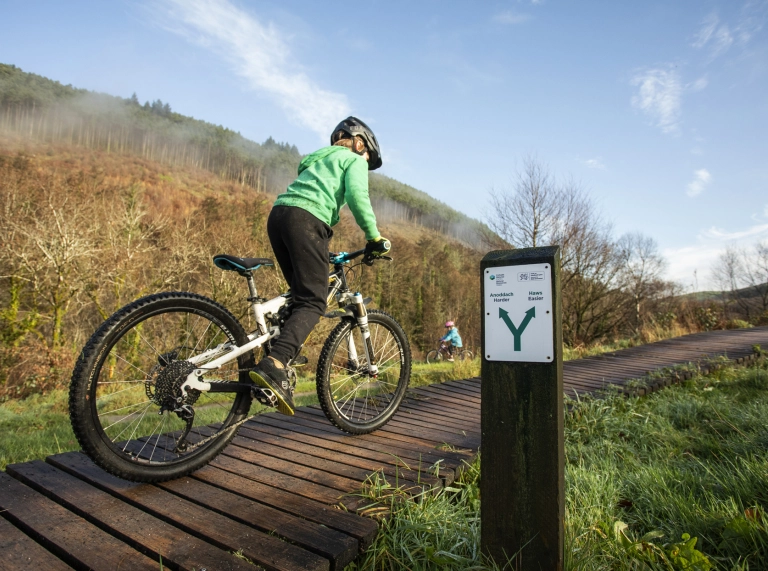 A child riding a mountain bike along a wooden boardwalk.