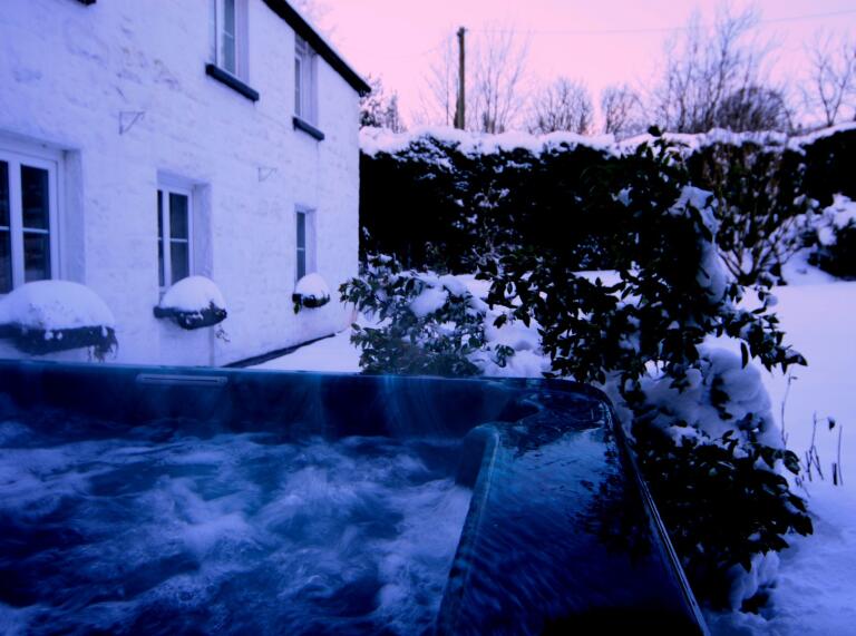 A bubbling hot tub in a snowy garden.