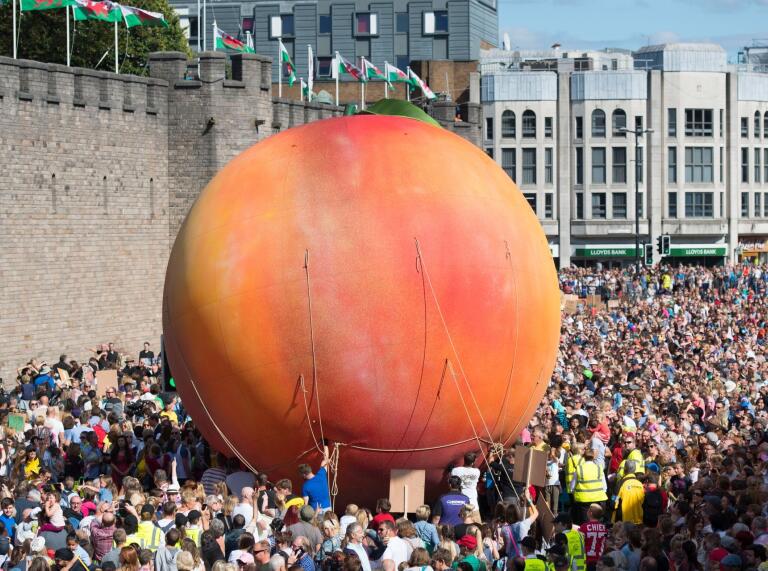 A giant inflatable peach and crowds by the castle in Cardiff.