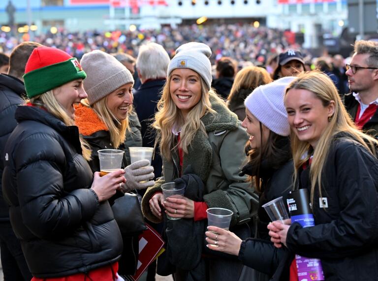 group of female rugby fans smiling and holding drinks.