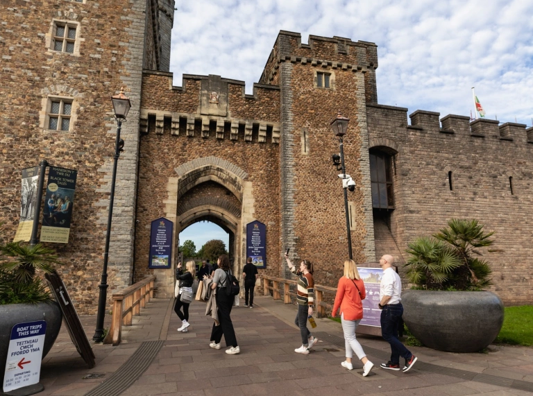 Entrance to a castle with people walking through a gatehouse.